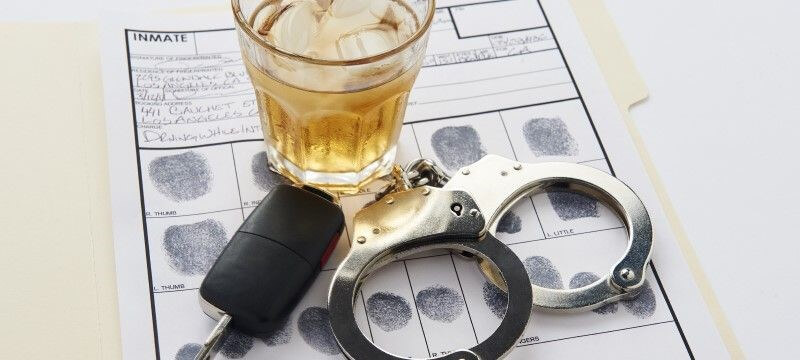 Handcuffs resting next to a glass of liquor