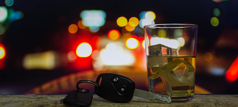 Keys resting next to a glass of liquor