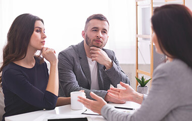 thoughtful young couple listening to confident financial advisor explaining something important