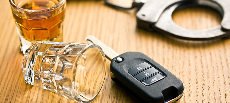 Car keys resting next to glasses of liquor