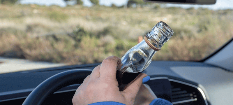 Person holding an open liquor container while driving.