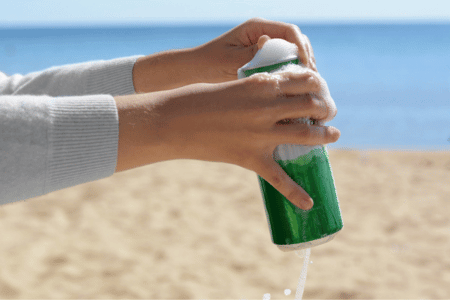 Person opening a foamy beer on a Florida beach