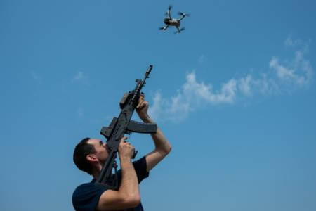 Person recklessly shooting a rifle into the sky at a drone