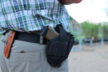 Person with a handgun on a holster using permitless carry laws