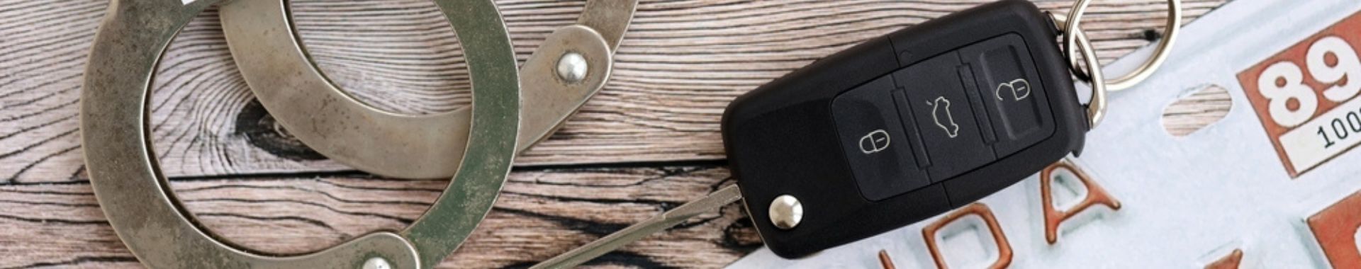 handcuffs, car keys, and florida drivers license on wood table