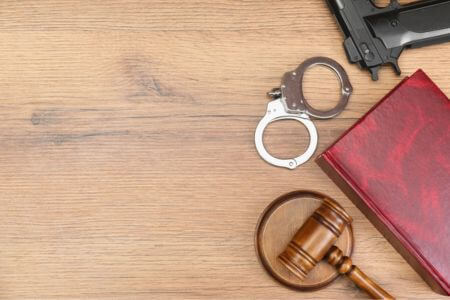 legal materials with a handgun and a court gavel on a desk.